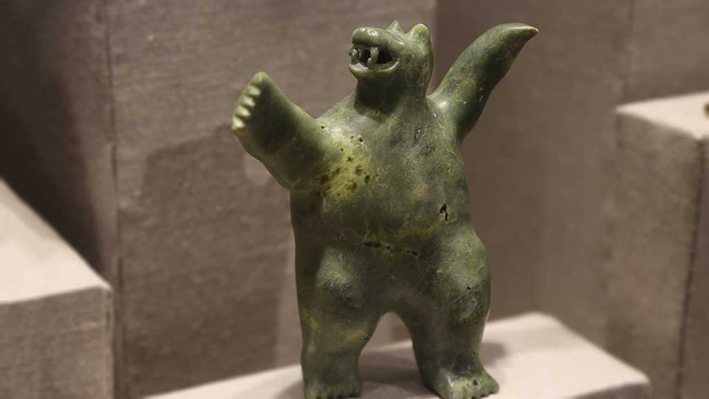 small green carving resembling a bear standing upright with arms in the air